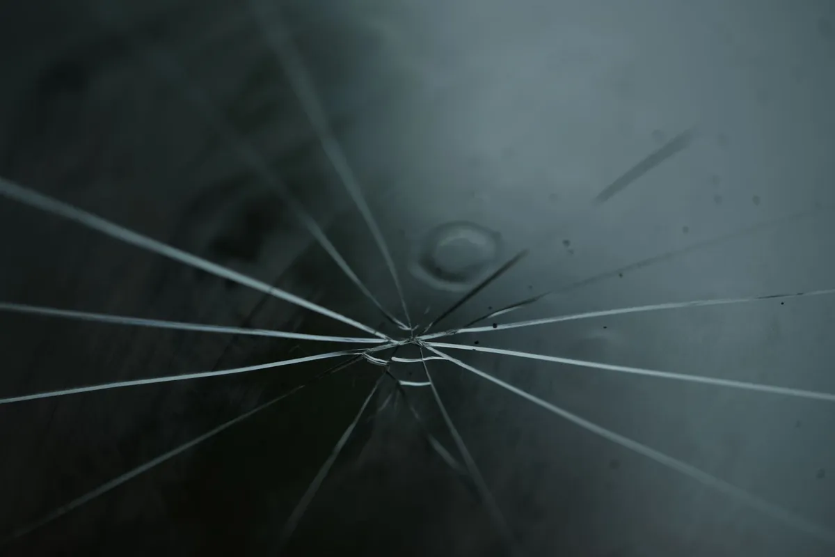 Close-up of cracked auto glass with radiating lines, illustrating common issues to identify early.
